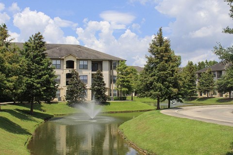 a fountain in the pond in front of a building